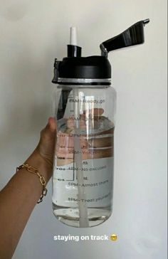 a person is holding up a water bottle with an open lid and straw in it