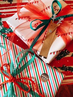 presents wrapped in red, green and white paper with bows on them sitting on top of each other