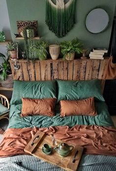 a bed that has some plants on the headboard and pillows in front of it