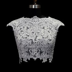 a white lace top on a mannequin headdress in front of a black background