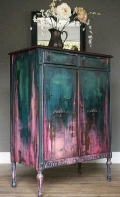 a painted cabinet with flowers and a vase on top