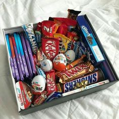 an open box filled with assorted candy and candies on top of a bed