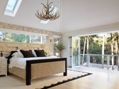 a bedroom with a bed, dressers and a chandelier hanging from the ceiling