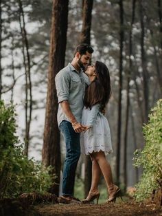 a couple kissing in the woods surrounded by trees