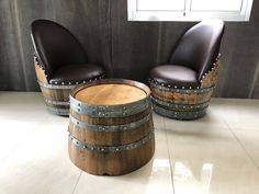 two black leather chairs sitting next to wooden barrels