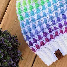 a crocheted hat sitting on top of a wooden table next to a potted plant