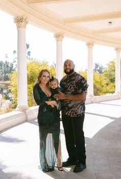 a man, woman and child standing in front of pillars