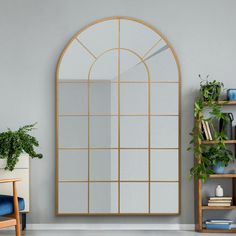 a living room with a large arched window and bookshelf on the wall next to it