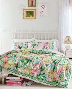 a white bed with pink and green comforter