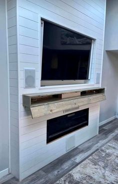 a flat screen tv mounted to the side of a wall in a room with wood flooring