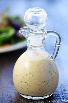 a small glass bottle filled with dressing on top of a table