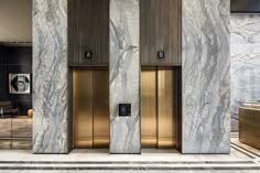 two elevators are in the middle of a marble lobby