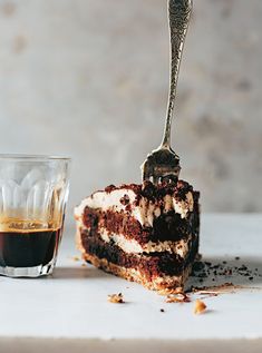 a piece of cake on a plate with a fork in it next to a cup of coffee