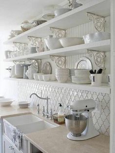 a kitchen shelf filled with white dishes and appliances