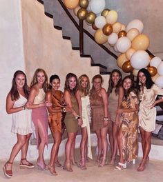 a group of young women standing next to each other in front of a stair case