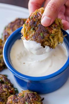 a person dipping something into a small blue bowl filled with cream cheese and other appetizers