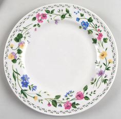 a white plate with colorful flowers and leaves painted on the rim, sitting on a table