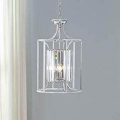 a light fixture hanging from the ceiling in a room with white walls and curtains behind it