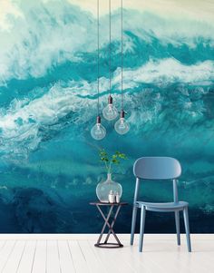 a chair and table in front of a wall with an ocean painting on the wall