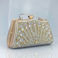 Adorned with beads and gems arranged in a mesmerizing starburst pattern, this clutch is a true statement piece that radiates sophistication and style. The Valerie Diamonds Handbag features a spectacular design, enhanced by a chic metal handle and a detachable chain strap. Available in luscious colors, this clutch is crafted with top-notch quality, ensuring it remains a timeless addition to your collection. Now available in blue, gold, and silver. Glamorous Gold Handheld Clutch, Glamorous Bling Clutch For Events, Elegant Sparkling Clutch Evening Bag, Elegant Bedazzled Rectangular Evening Bag, Luxury Bedazzled Evening Bag For Party, Glamorous Gold Clutch With Pearl Handle, Elegant Handheld Evening Bag With Bling, Glamorous Bedazzled Rectangular Evening Bag, Elegant Bedazzled Bag For Events