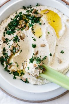 a white plate topped with mashed potatoes covered in cream sauce and chopped green onions