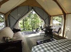 the inside of a tent with a bed, table and chairs