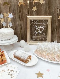 a table topped with cakes and desserts next to a wooden fence covered in stars