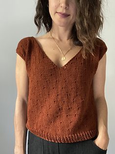 a woman in an orange sweater is posing for the camera with her hands on her hips