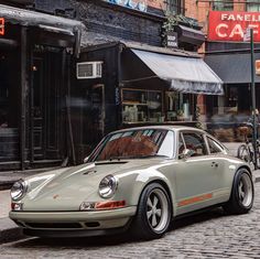 a white car parked on the side of a street next to a brick sidewalk with people walking by