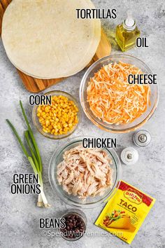 ingredients to make mexican chicken burritos laid out on a cutting board, including corn, cheese, black beans, tortilla flour and green onions