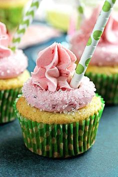 cupcakes with pink frosting and sprinkles are on a table