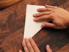 two hands holding a piece of paper on top of a wooden table