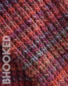 closeup of an orange and pink knitted blanket with the words hooked on it