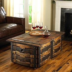 a wooden table with wine glasses on it in front of a leather couch and fireplace