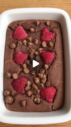 a chocolate dessert with raspberries and chocolate chips on top in a white dish