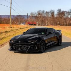 a black chevrolet camaro is parked on the road