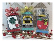 three handmade wooden signs with apples, trucks and school bus designs on them sitting next to candy canes