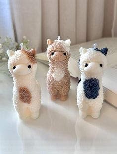 three little llamas are sitting next to an open book