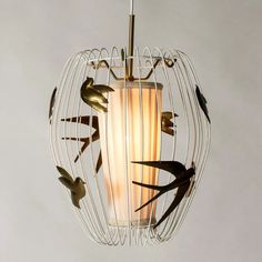 a light fixture with birds flying around it on a white wall behind the bird cage