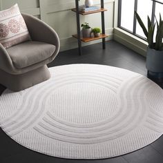 a round rug in the middle of a room with a chair and potted plant