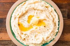 a bowl of mashed potatoes topped with butter and olive oil on a wooden table