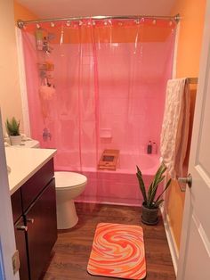 a bathroom with a pink shower curtain next to a toilet