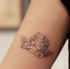 a small tattoo on the arm of a girl with an angel wings and a heart