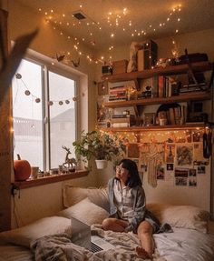 a woman sitting on top of a bed in front of a window next to a laptop computer