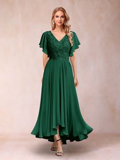 a woman is wearing a green dress with lace detailing on the shoulders and sleeves,