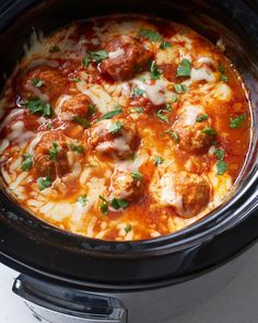 a slow cooker filled with meatballs and sauce