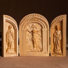 three carved wooden sculptures depicting jesus, mary and jesus on the cross in an arch