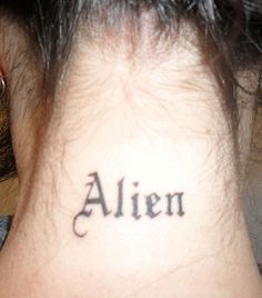 the back of a woman's neck with an inscription on it that reads alien