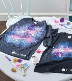 two children's shirts on a table with paint and play doughnuts next to them