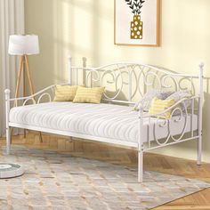 a white daybed sitting on top of a hard wood floor next to a lamp